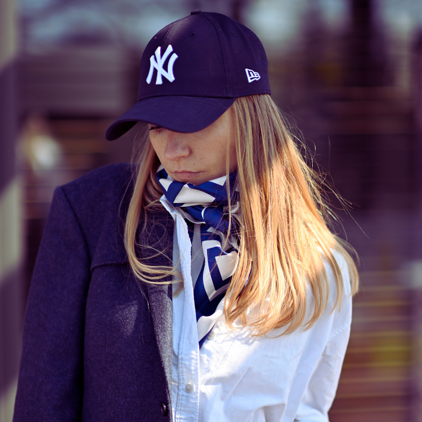 A model in a cap wearing a large blue and cream silk scarf