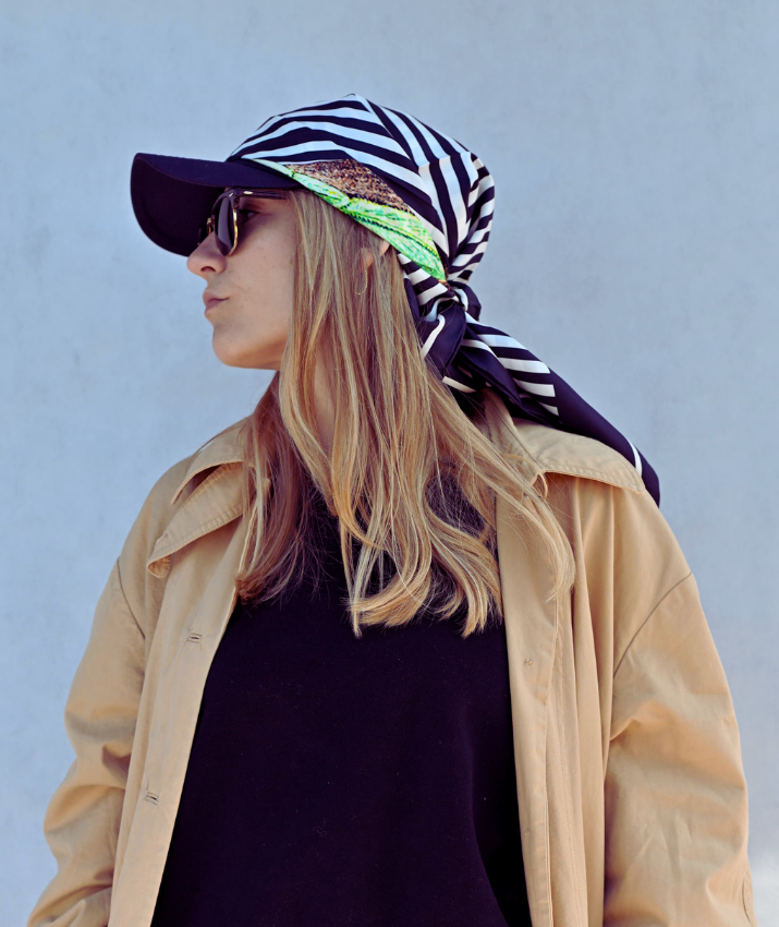 A model wearing a large black and green silk scarf with a hummingbird print. 100% Silk Mulberry scarf