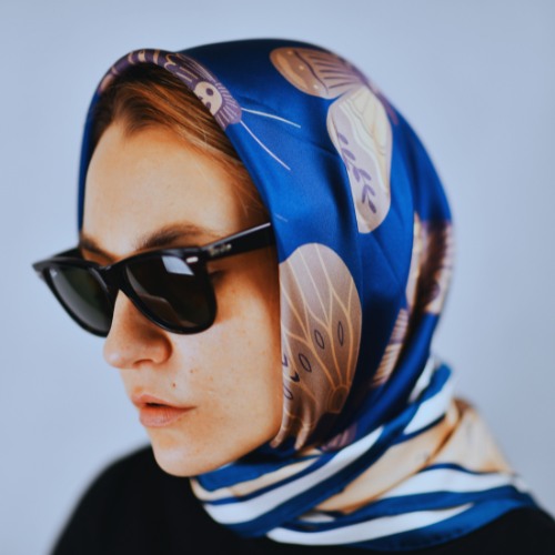 A model wearing a dark silk scarf as a head scarf