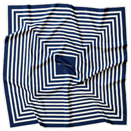 A model in a cap wearing a large blue and cream silk scarf