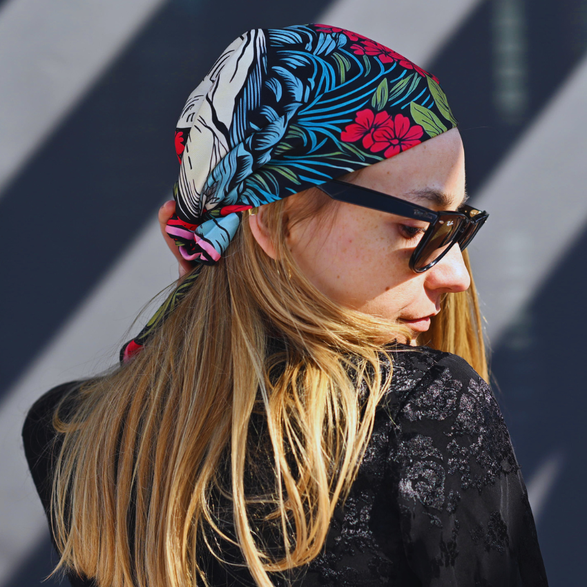 A model wearing a silk bandana, a floral red and black silk scarf
