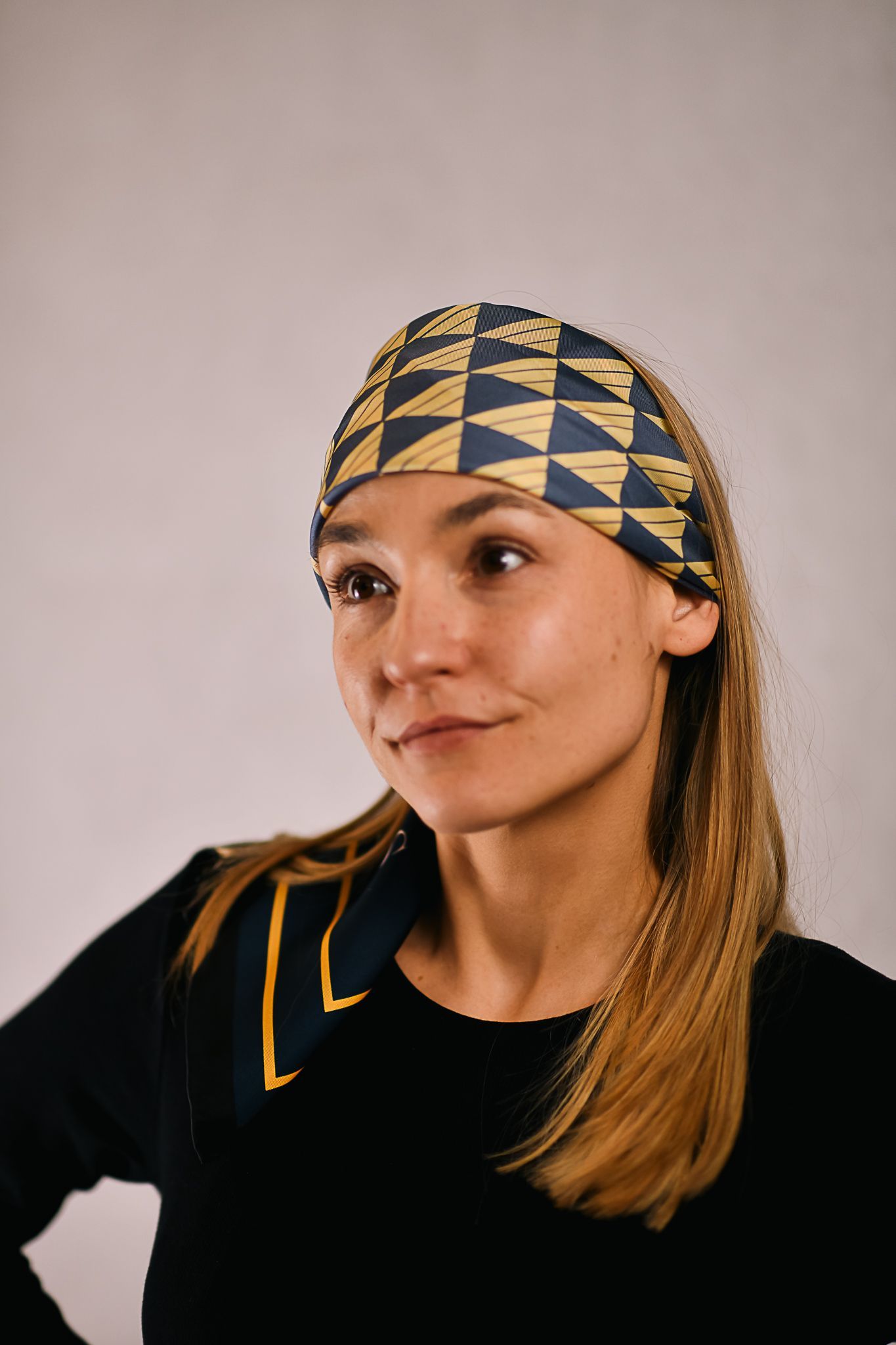 A model wearing an elegant art deco mulberry silk scarf for women, black , blue and gold
