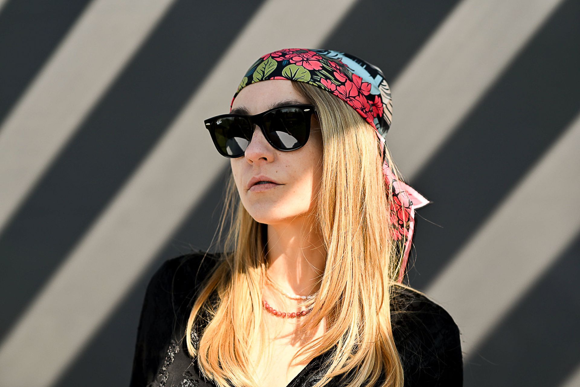 A model wearing a silk bandana, a floral red and black silk scarf