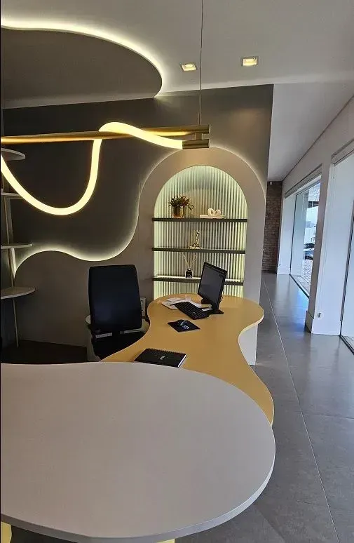 Escritório planejado em Curitiba: home office moderno com mesa de design orgânico, painéis de parede curvos com iluminação LED e estante embutida em arco.