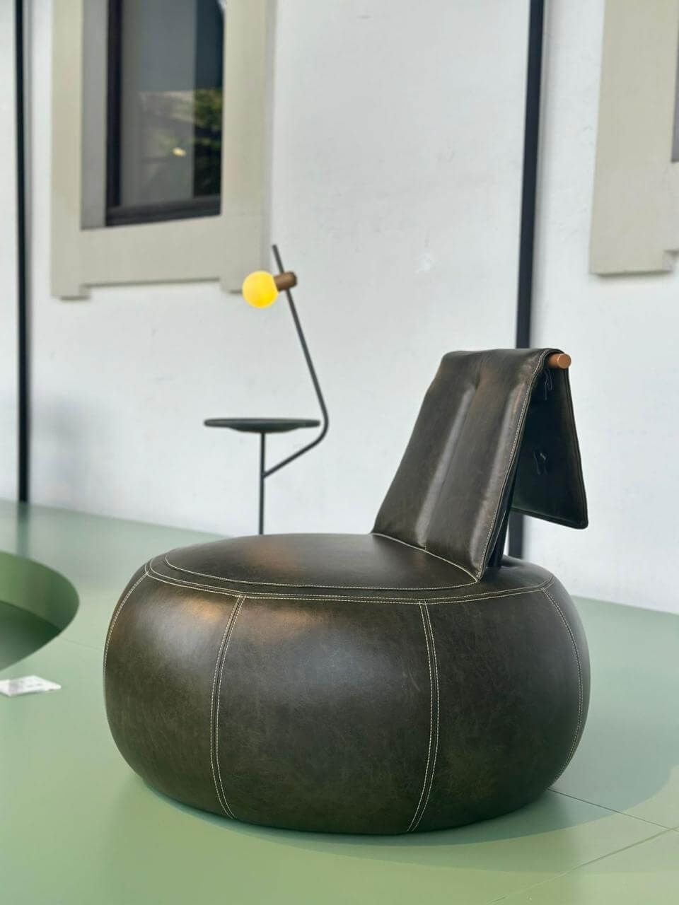 Poltrona de couro preta com design contemporâneo, estrutura robusta e acabamento de alto padrão. Acompanha mesa de apoio lateral integrada, ideal para ambientes sofisticados e funcionais.