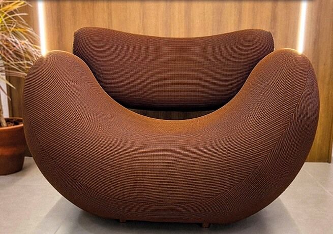 Poltrona orgânica marrom com design exclusivo, linhas curvas e acabamento de alto padrão. Estrutura robusta em madeira maciça, estofamento confortável e visual sofisticado.