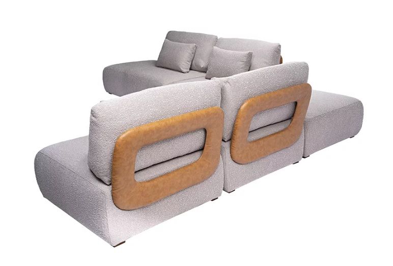 Sofá home de alto padrão em Curitiba, formato curvo com chaise, revestido em tecido claro, múltiplas almofadas decorativas e pés finos pretos, perfeito para ambientes sofisticados.