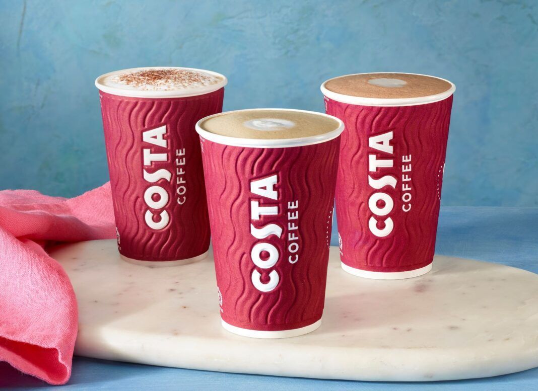 Three cups of costa coffee are sitting on a marble cutting board.