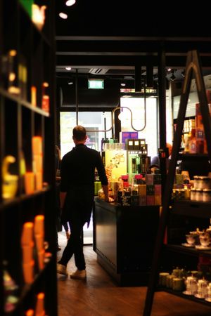 A man is walking through a store filled with lots of products.