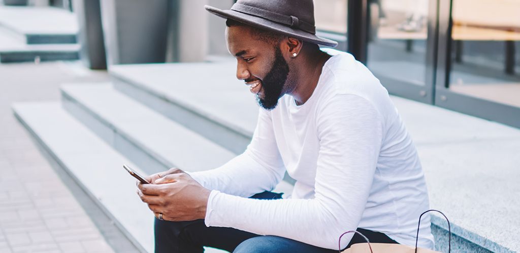 A man is sitting on a set of stairs looking at his cell phone.