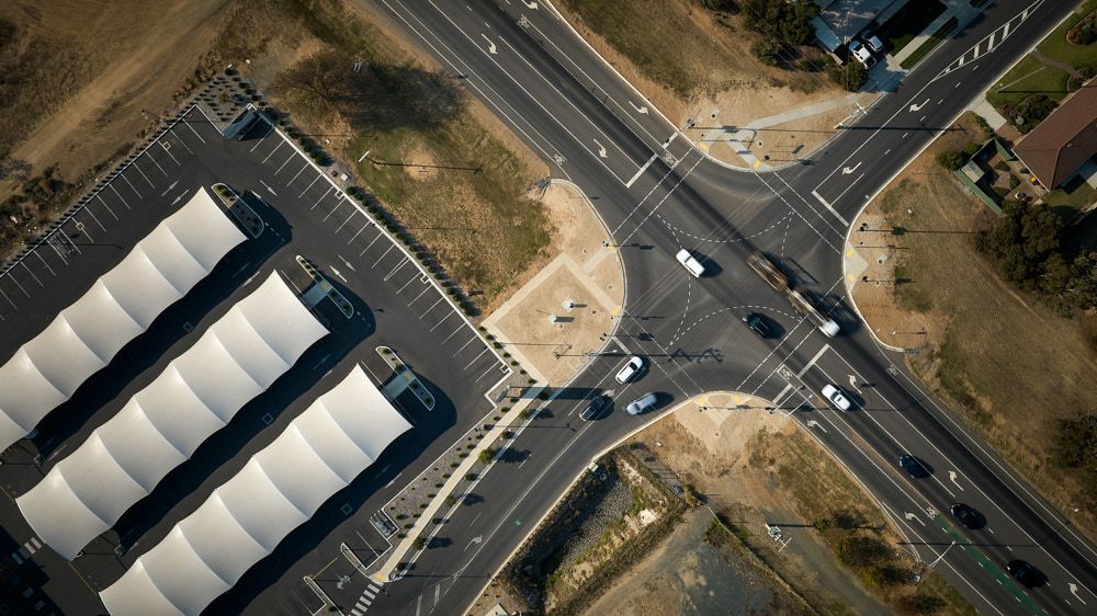 Aerial view of a road intersection beside a large parking lot with a long white-roofed building — Quarrell Civil Construction In Congupna, VIC