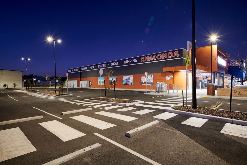 An exterior view of an Anaconda outdoor store at dusk, featuring a lit parking lot with marked pedestrian crossings — Quarrell Civil Construction In Congupna, VIC
