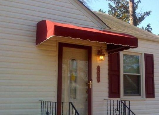 Red awning over a front door and window on a light-colored house