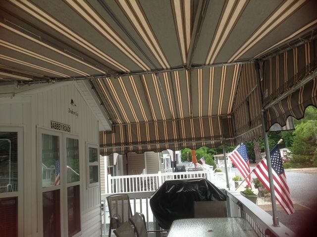 Beige and brown striped awning over a patio with outdoor furniture