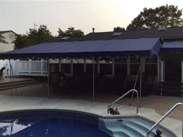 Blue awning over a patio next to a swimming pool.