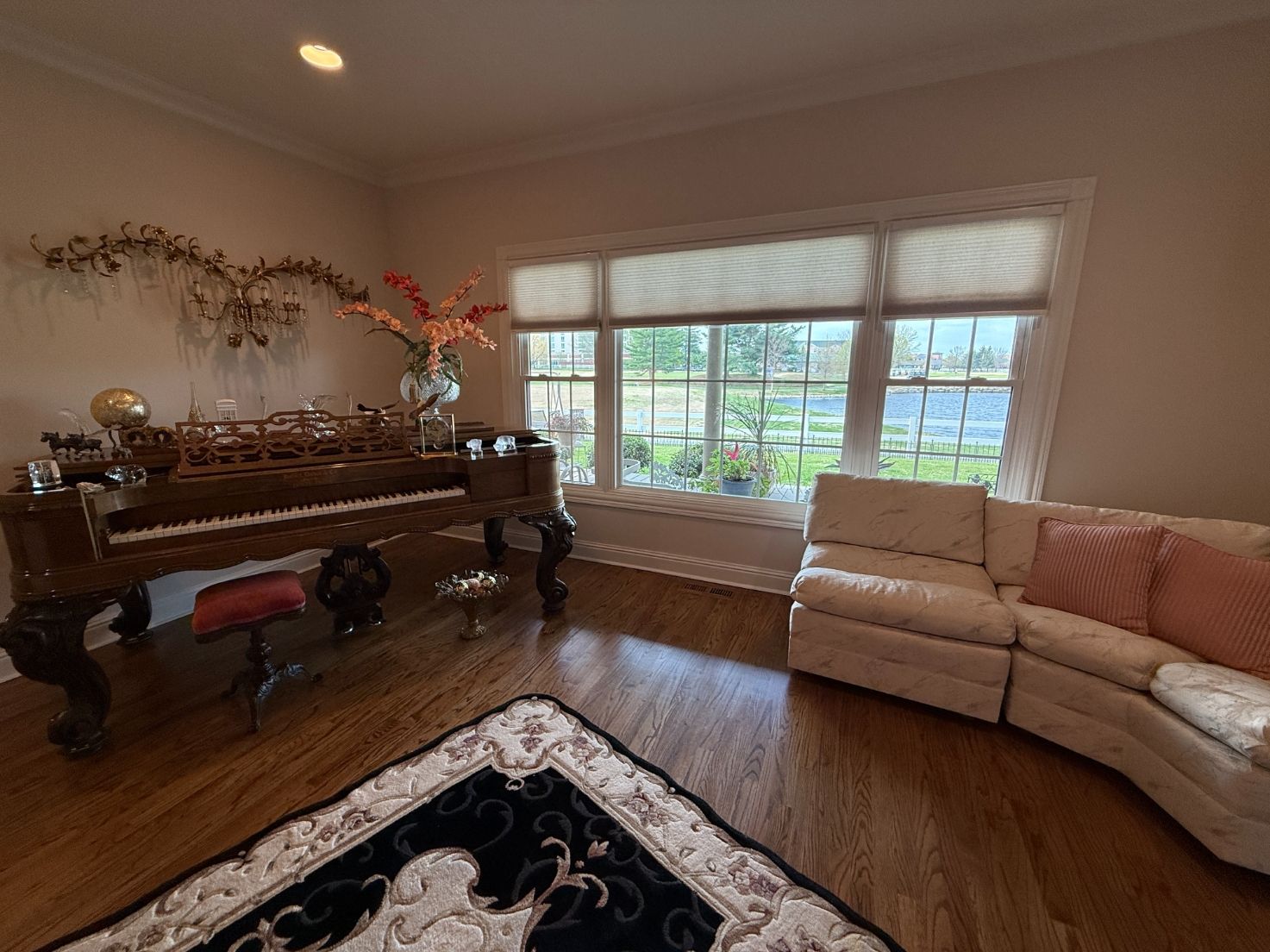 Elegant living room with piano, cream sectional, and large window seating area