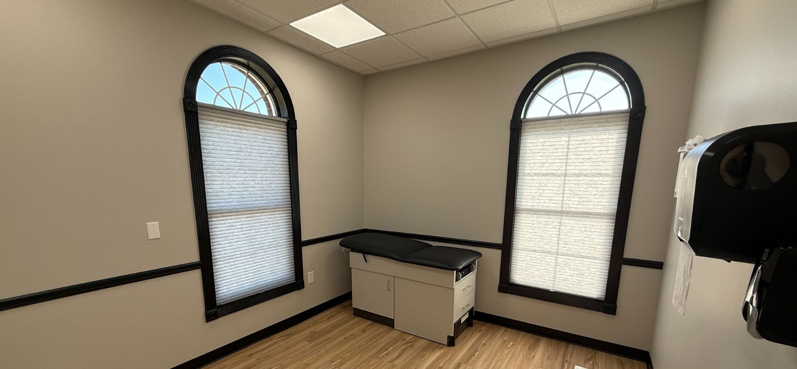 Small room with two arched windows, black countertops, and a cabinet or sink in the corner.