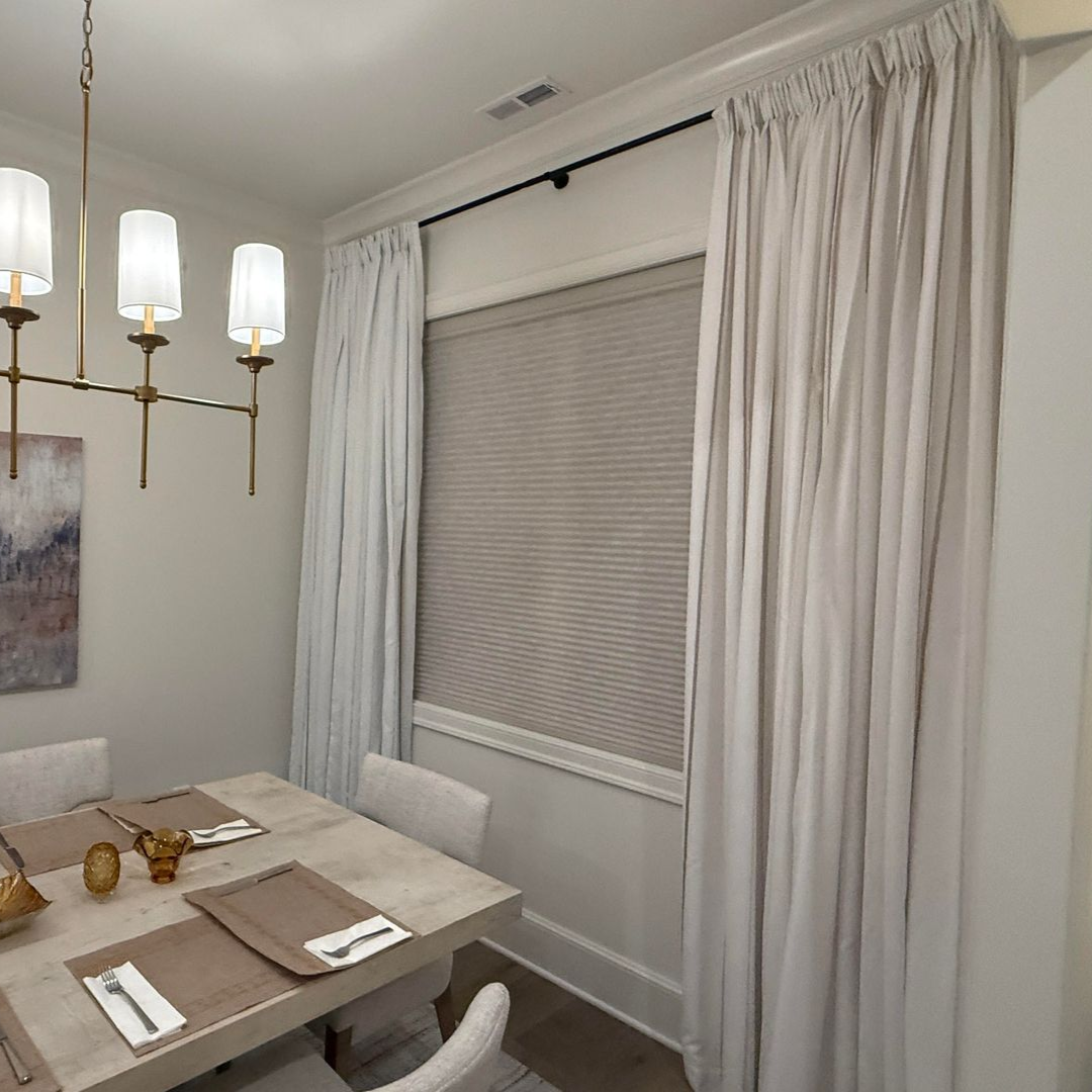 Dining room with a table set for a meal, a window, and sheer curtains.