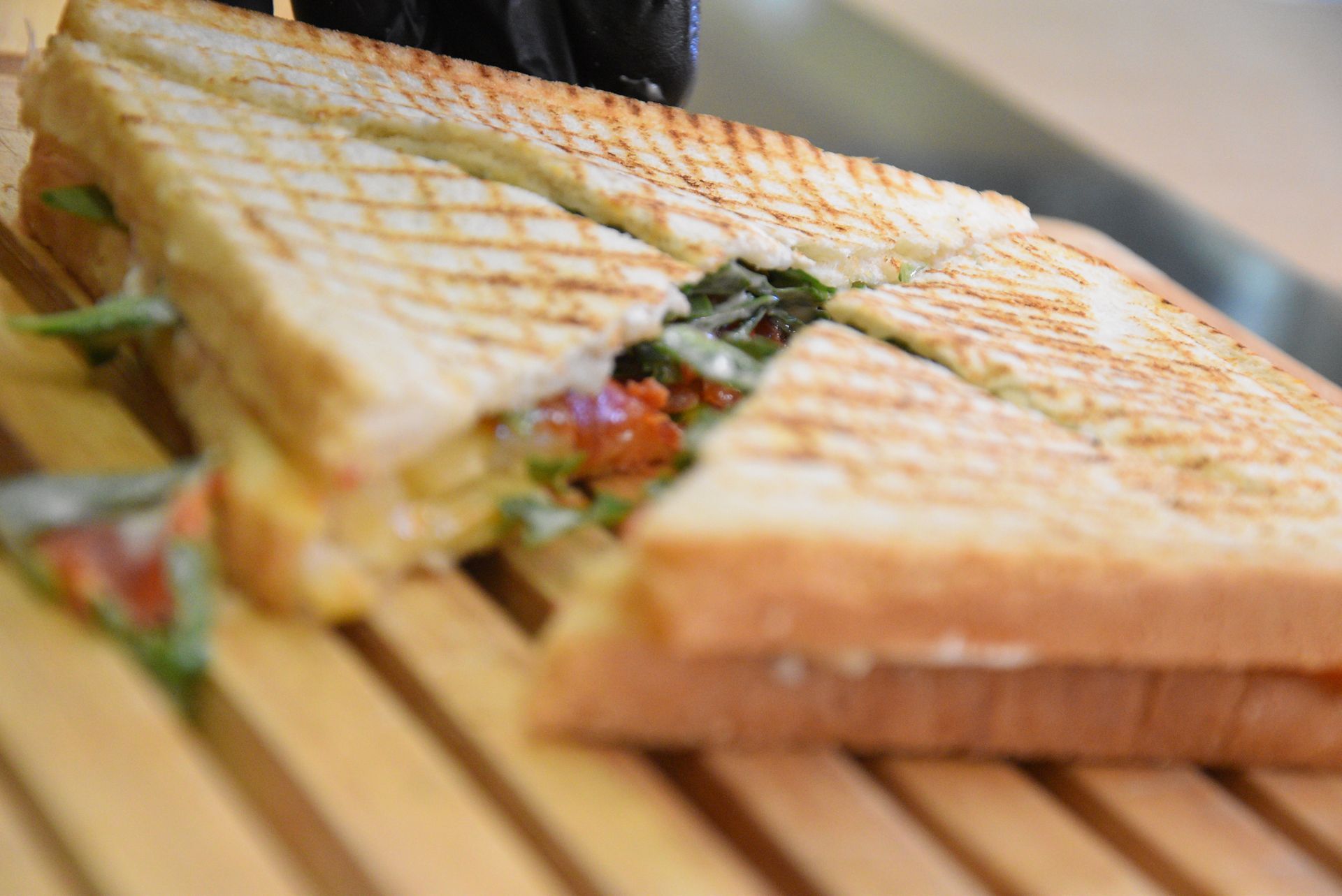 Panino grigliato tagliato a metà, su un tagliere di legno; ripieno visibile.