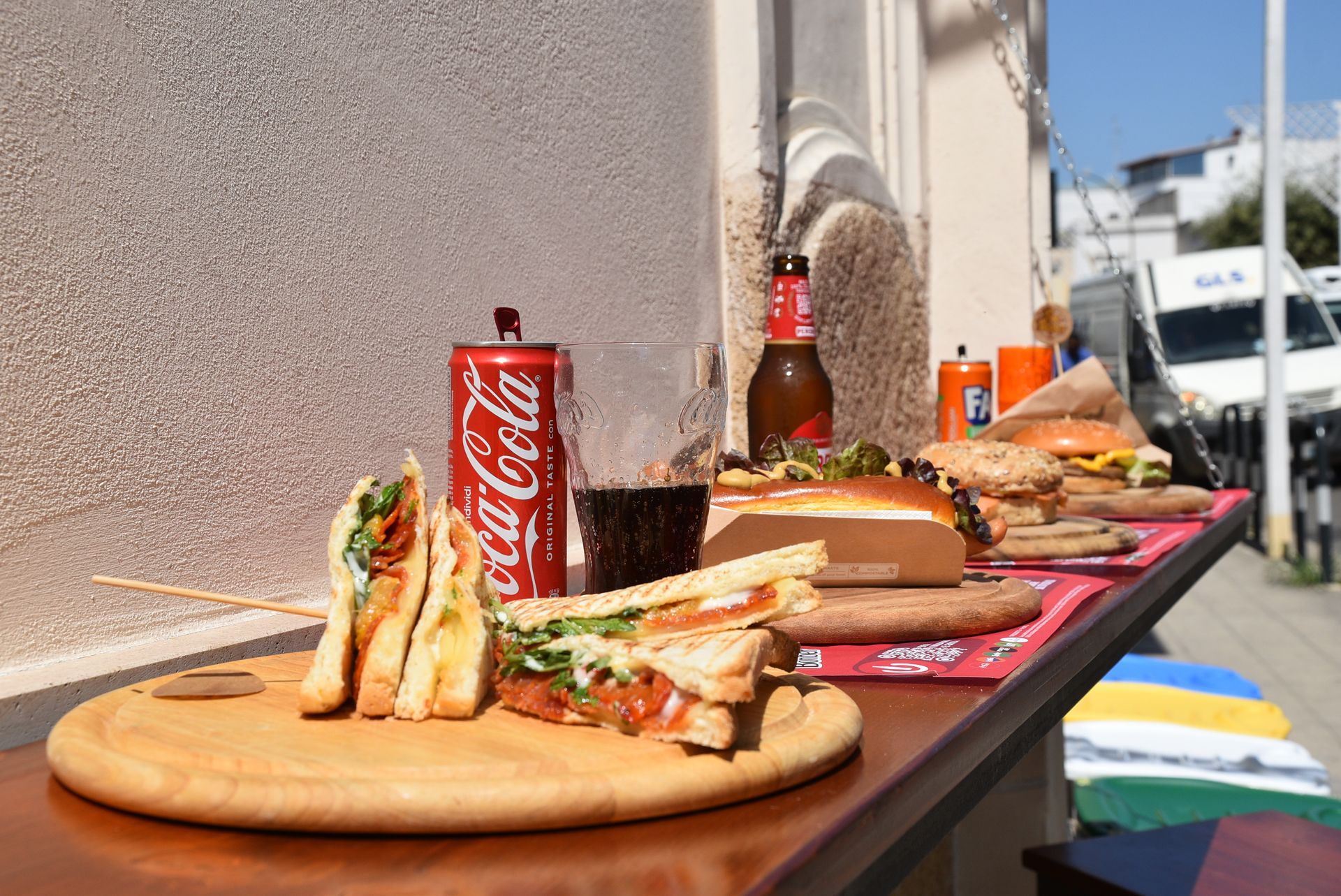 Panini, hamburger e Coca-Cola esposti su un bancone di legno lungo la strada.