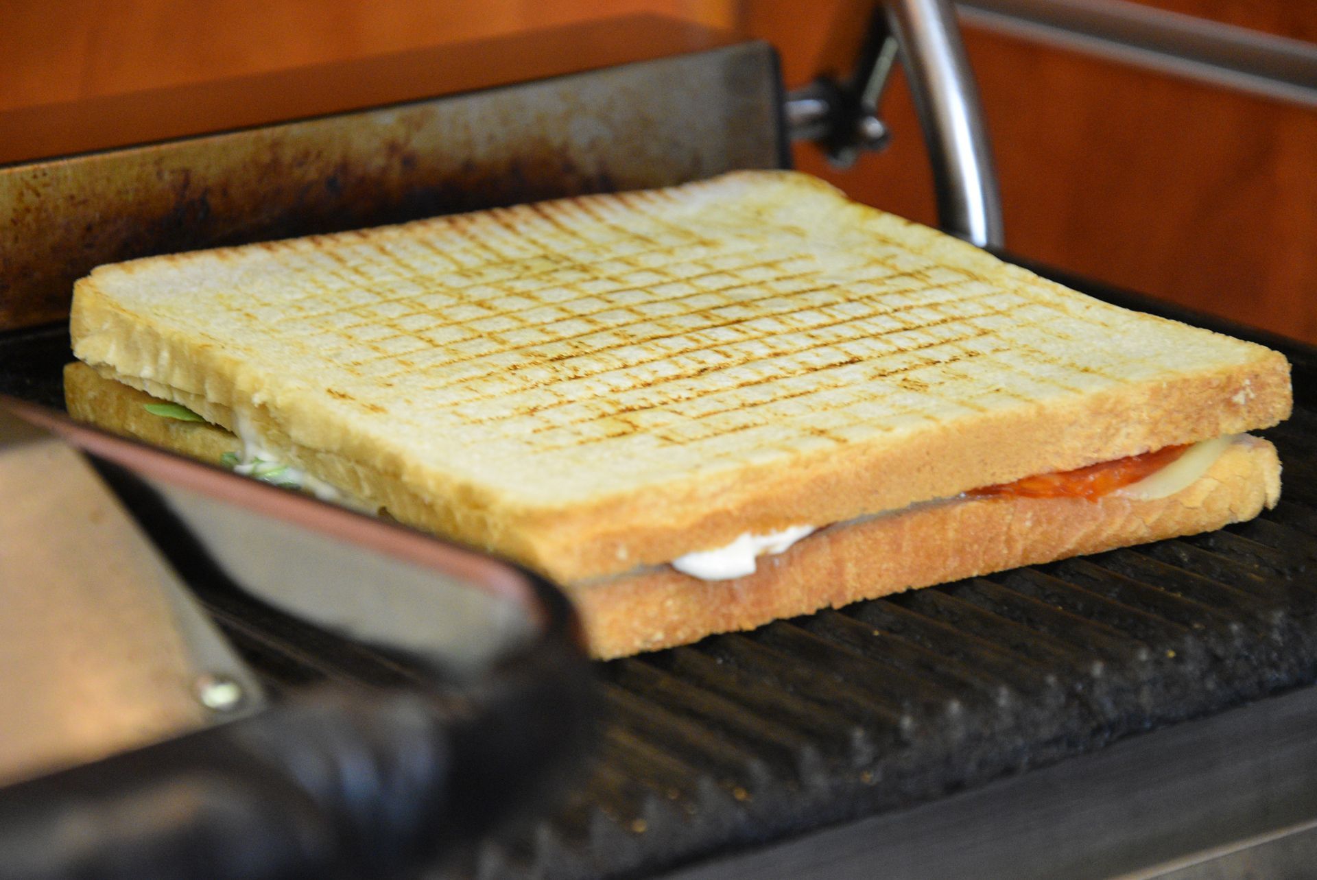 Panino grigliato su una piastra per panini; dorato, con i segni della griglia.