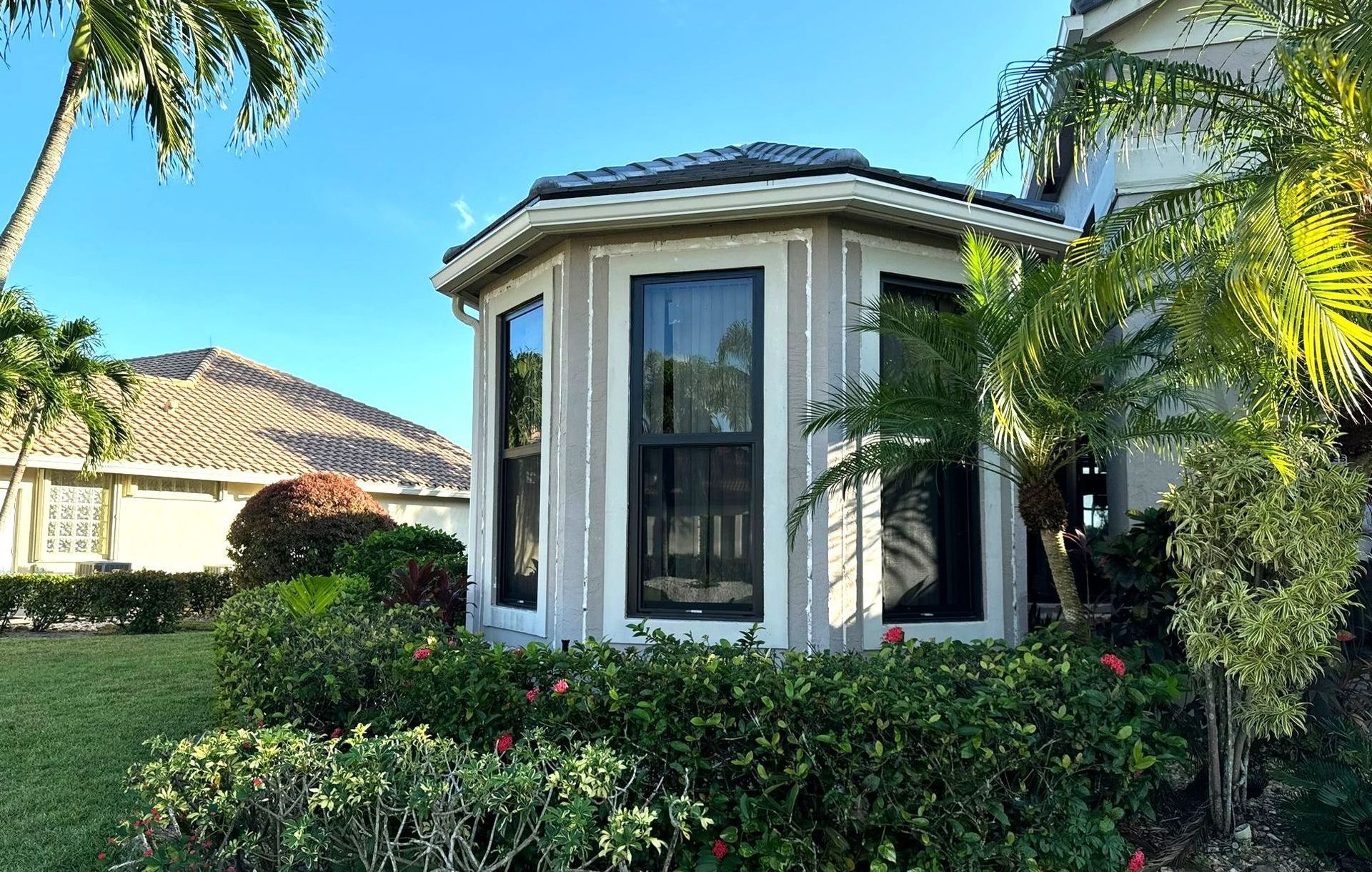 A house with a lot of windows and bushes in front of it