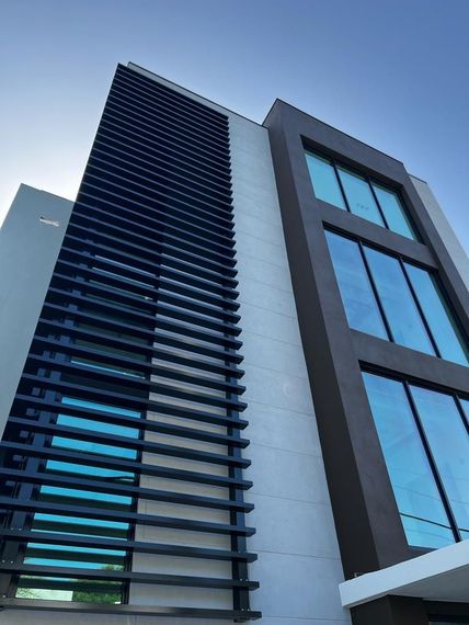 A tall building with a lot of windows and a blue sky in the background