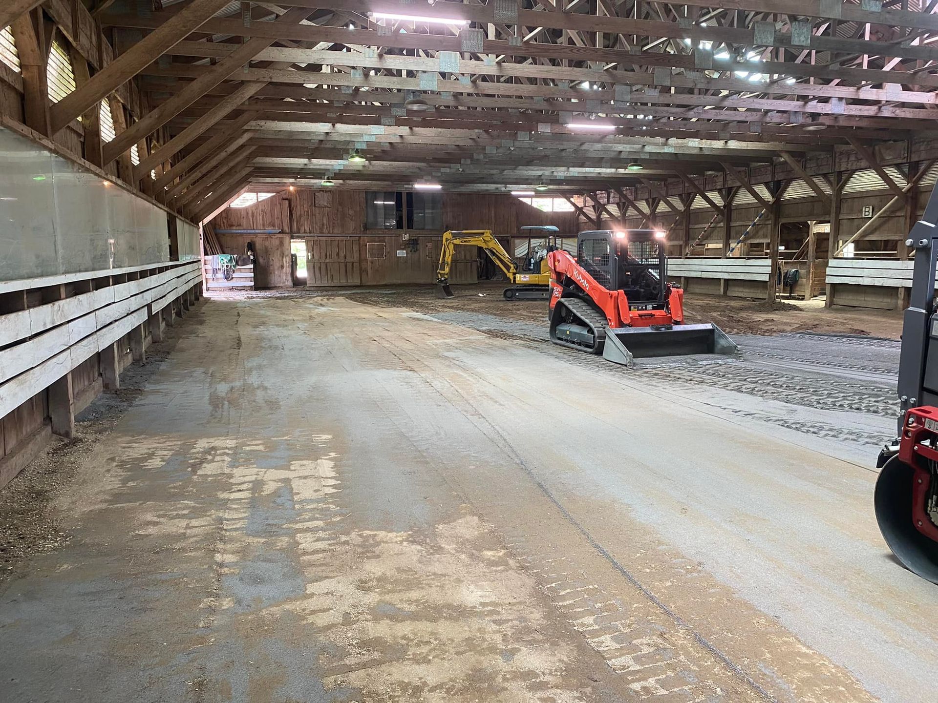Interior of a barn under construction with heavy machinery.
