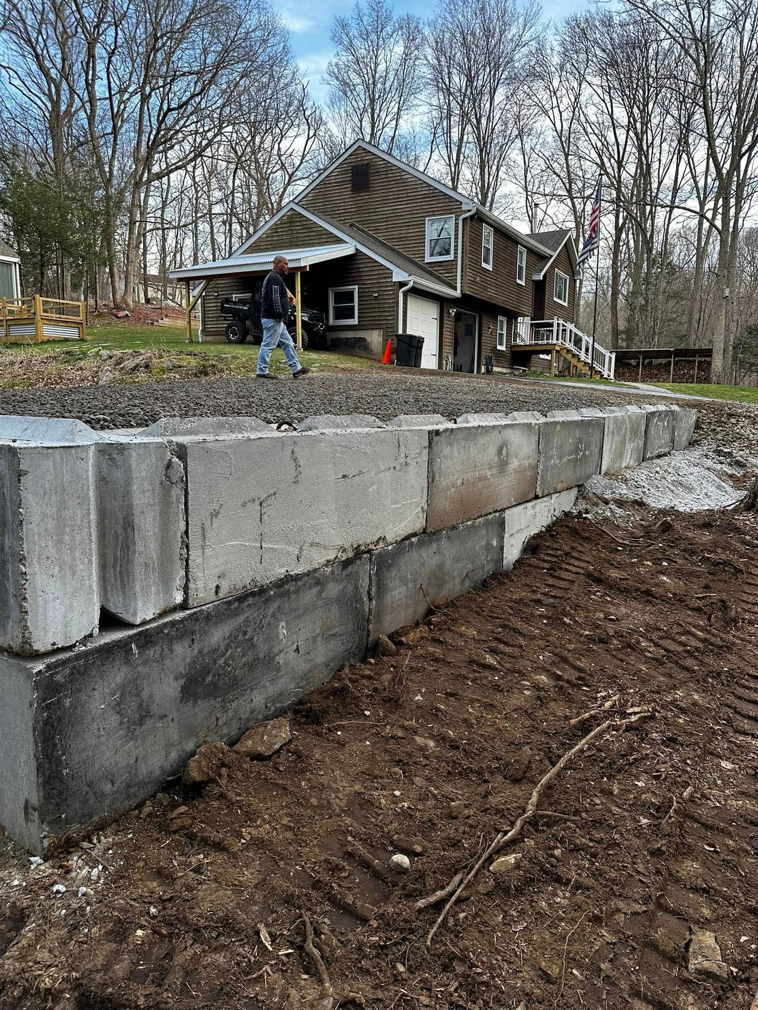 Construction of a cinder block retaining wall near a house; a person is working with a shovel.