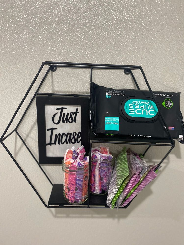 A shelf with wipes , tampons , and a picture on it.