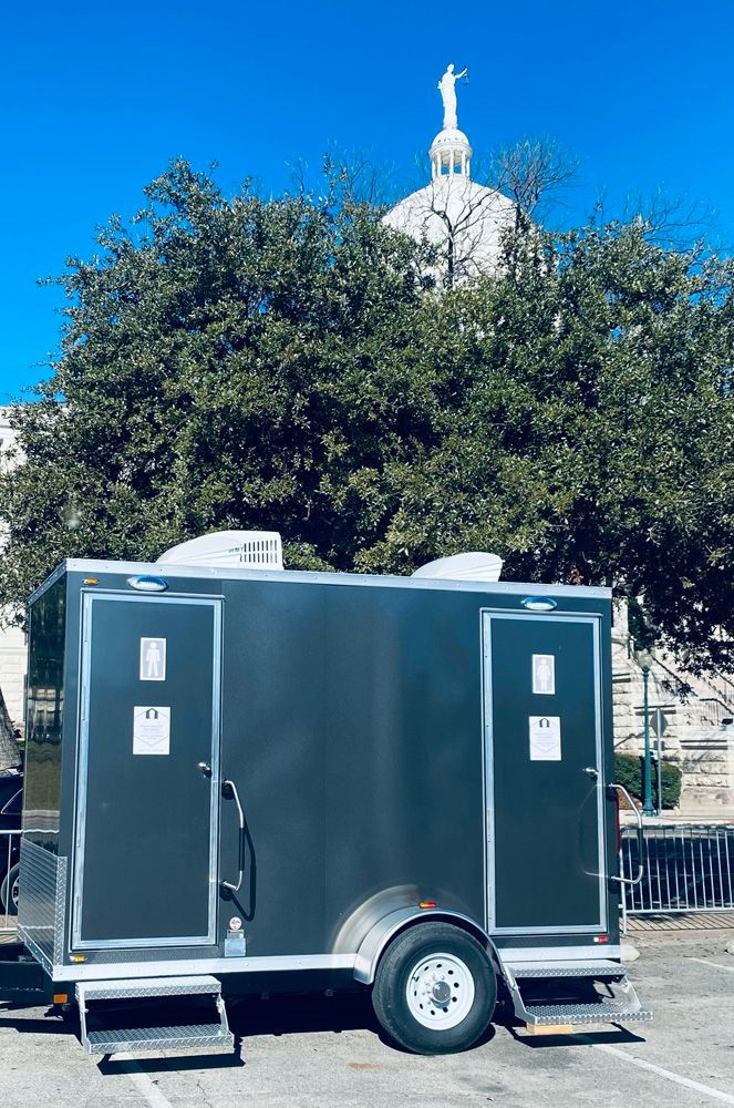 A trailer with two toilets on it is parked in front of a building.