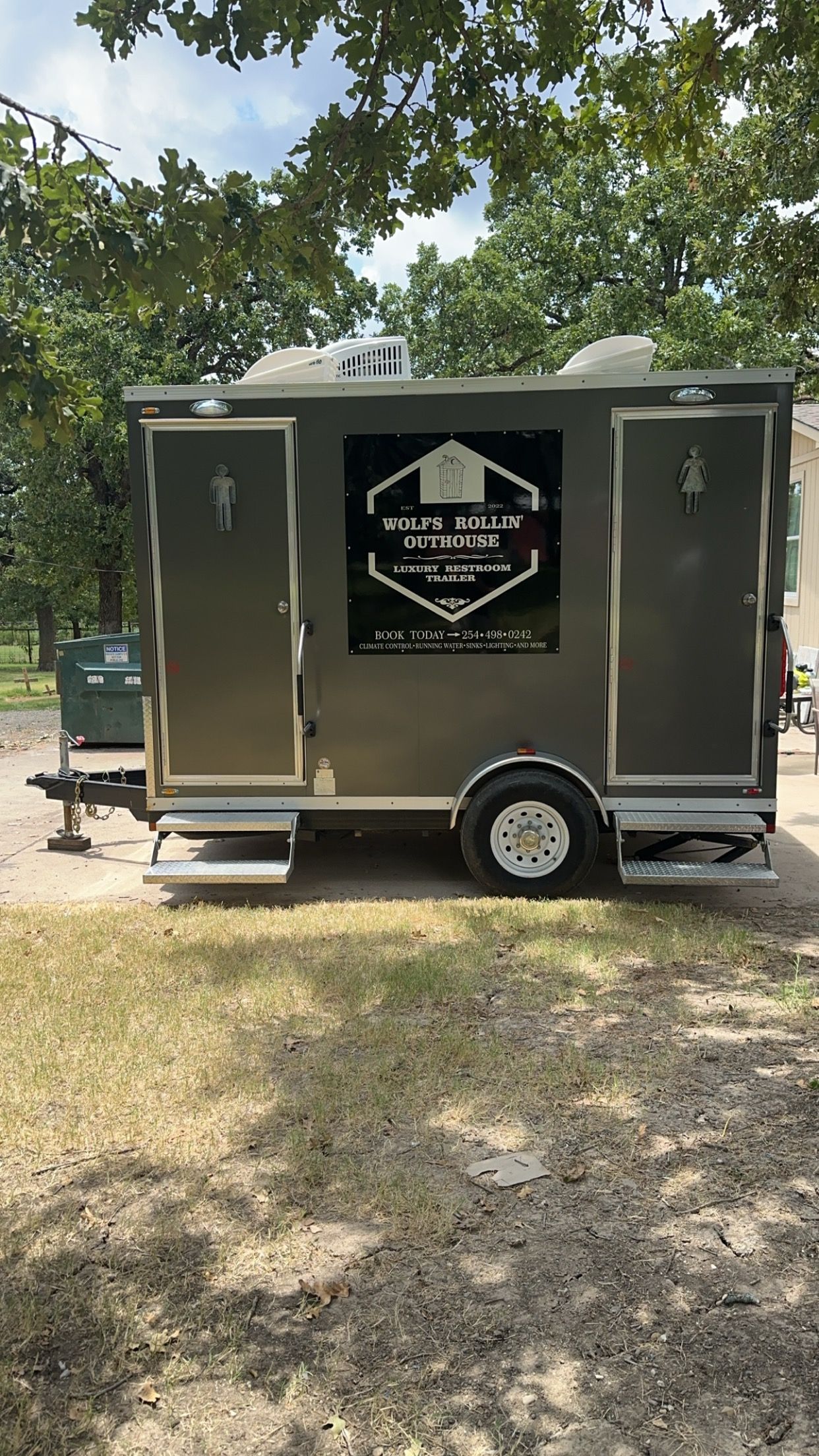 A trailer is parked in the grass in a park.
