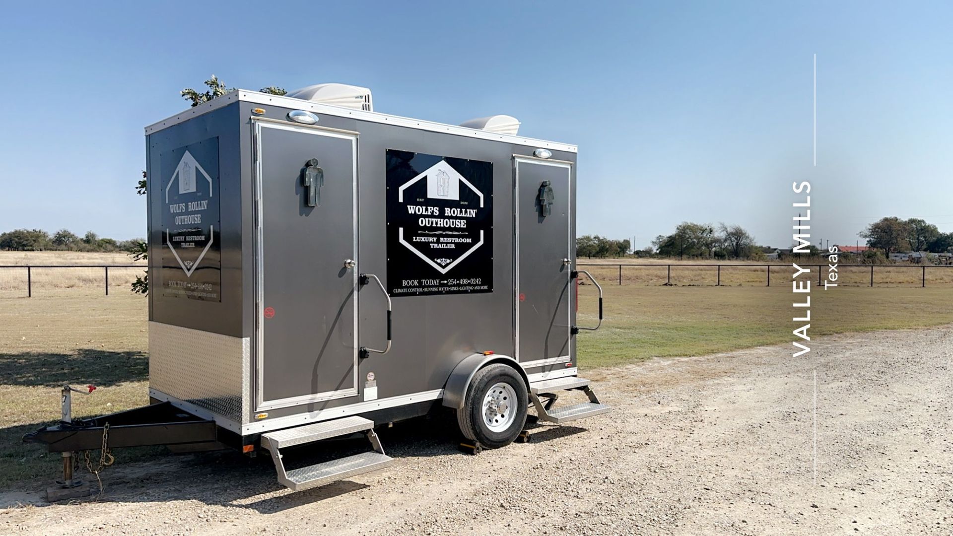 A trailer is parked in a gravel lot in a field.