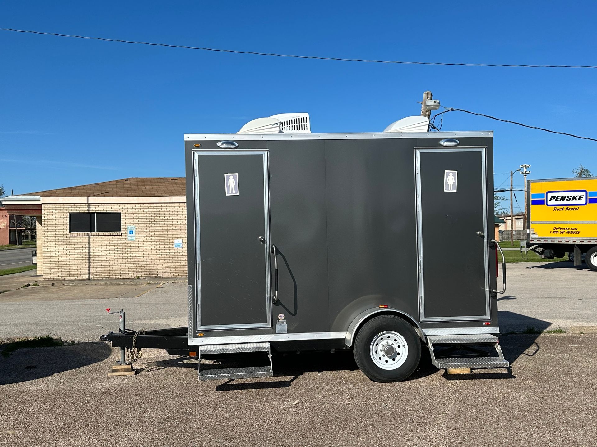 A trailer with two toilets on it is parked in front of a building.