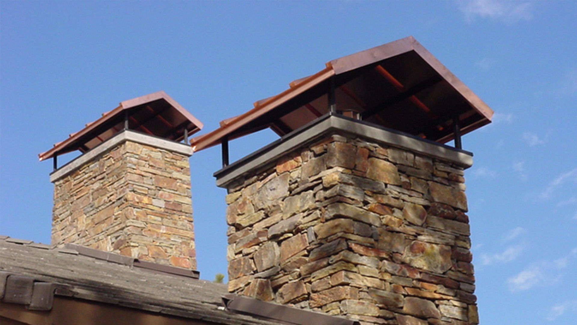 A couple of chimneys on top of a building with a blue sky in the background.