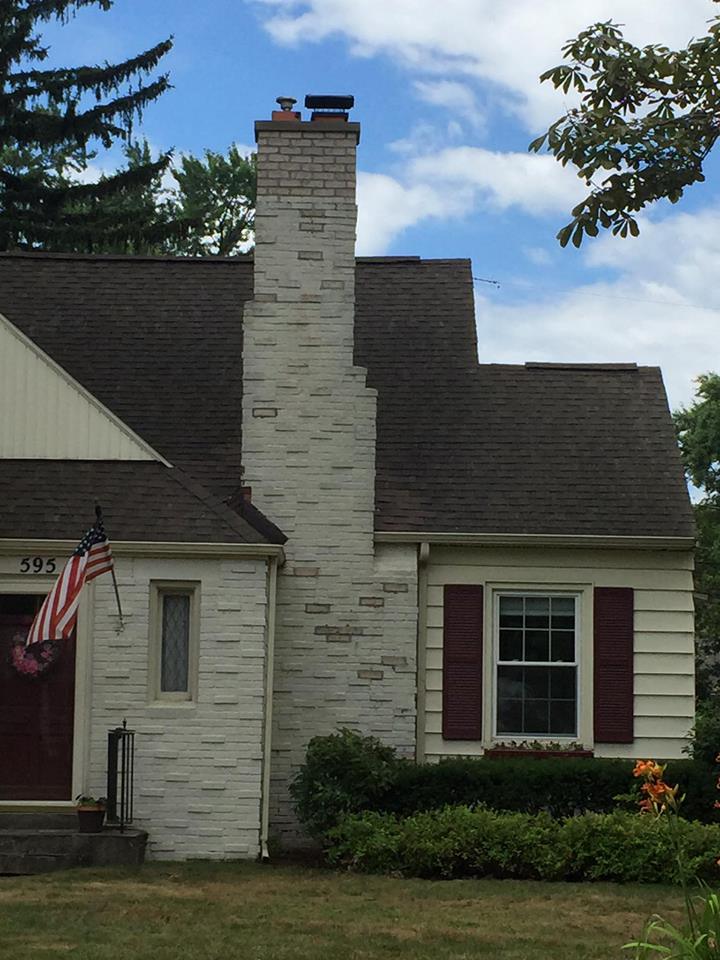 A white house with red shutters and an american flag