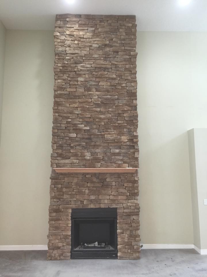 A stone fireplace with a mantle in a living room