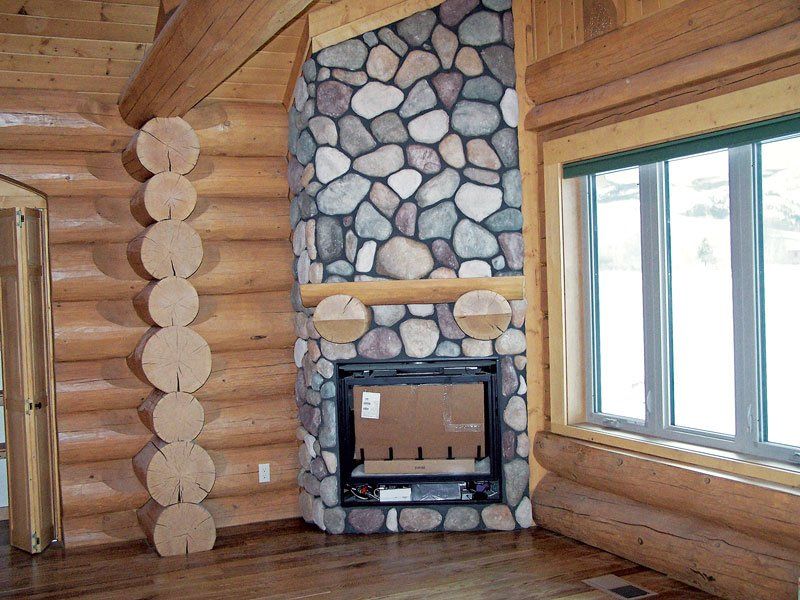 A log cabin with a stone fireplace and windows