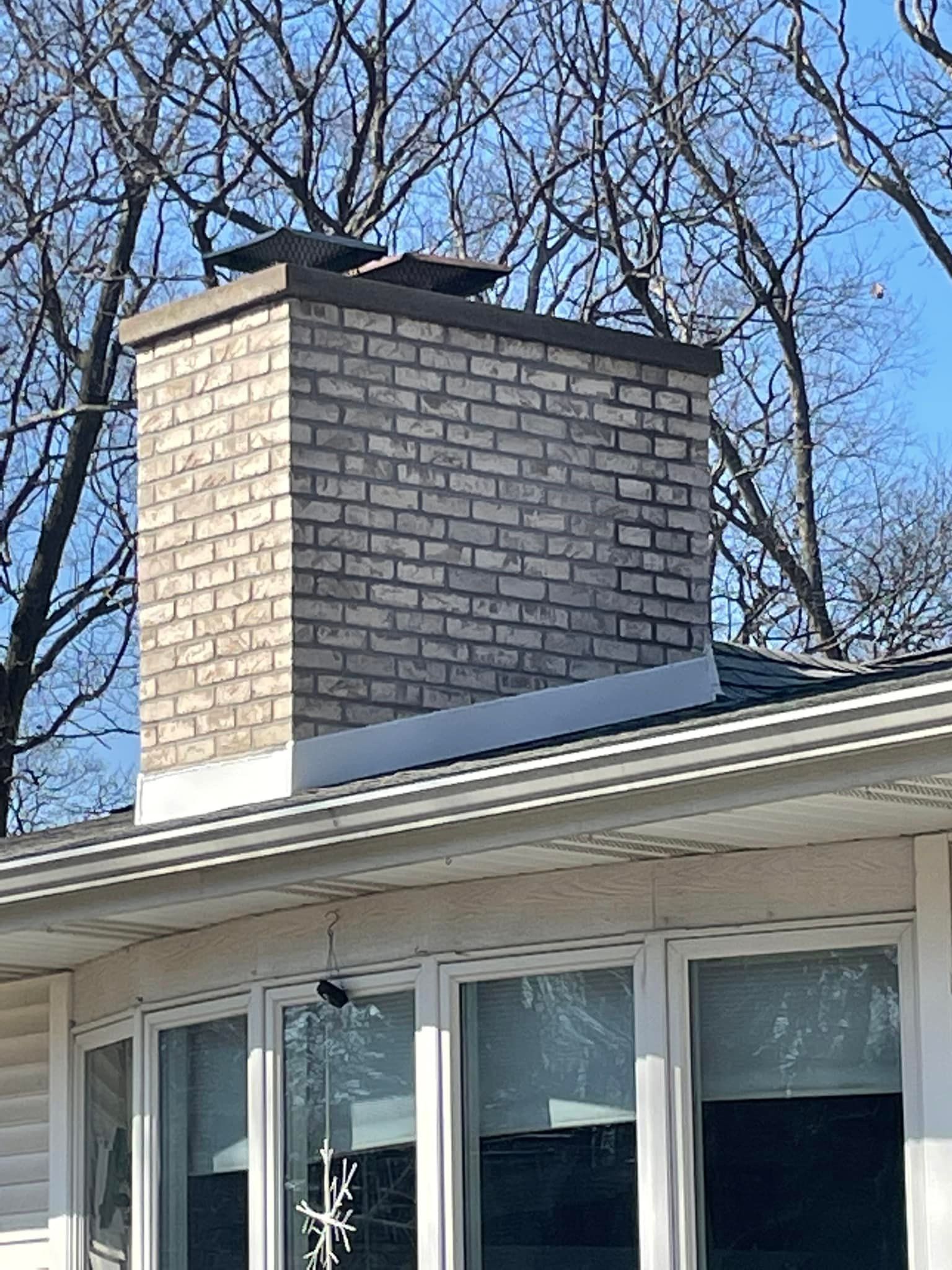 A brick chimney is on the roof of a house.