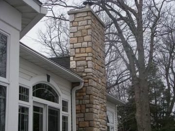 A large stone chimney on the side of a house