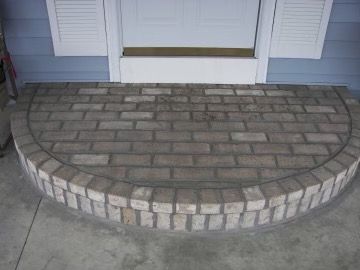 A brick porch with a white door in the background