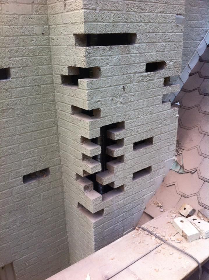 A brick wall with holes in it is being repaired