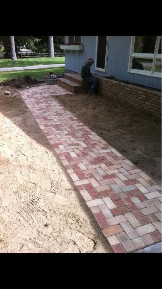 A brick walkway is being built in front of a house.