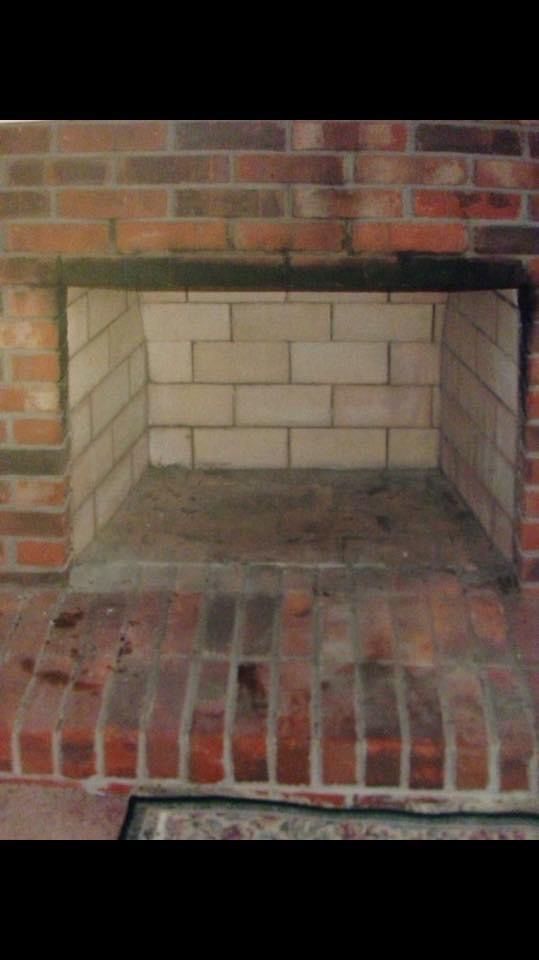 An empty brick fireplace with a metal frame.