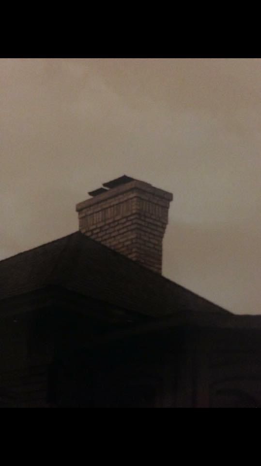 A chimney on top of a house with a cloudy sky in the background
