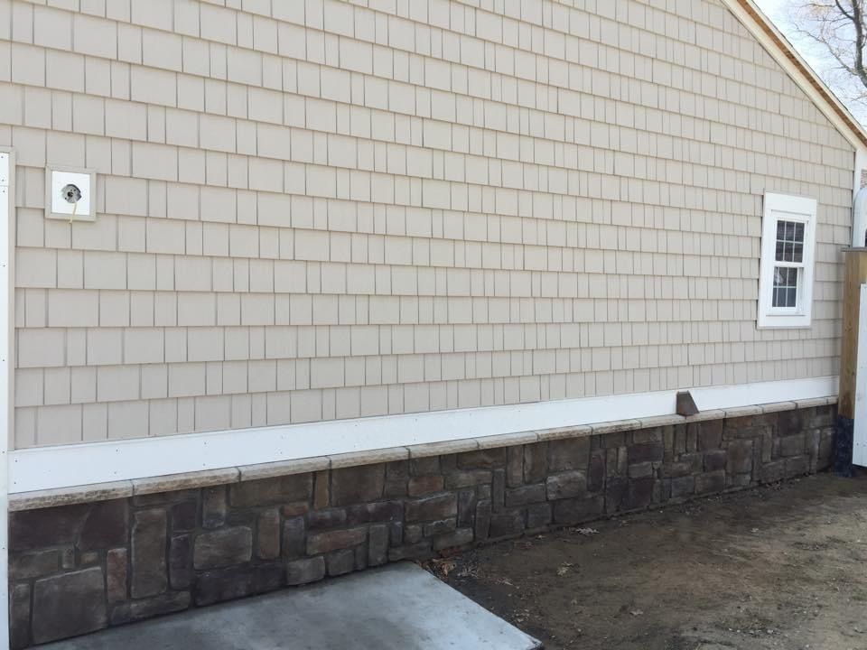 The side of a house with a stone wall and a window