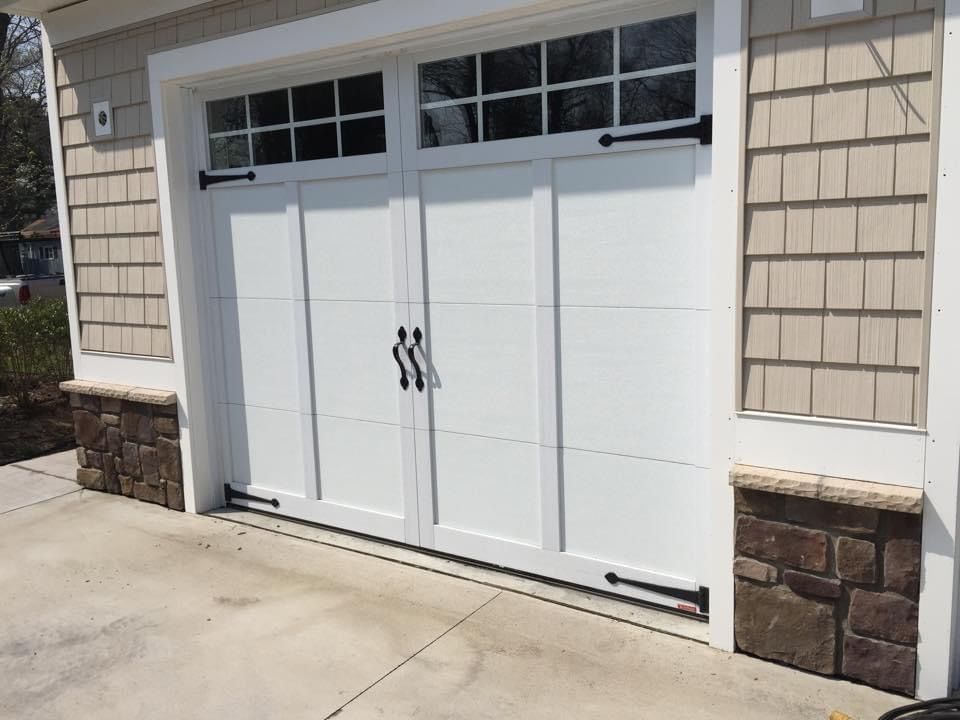 A white garage door is sitting on the side of a house.