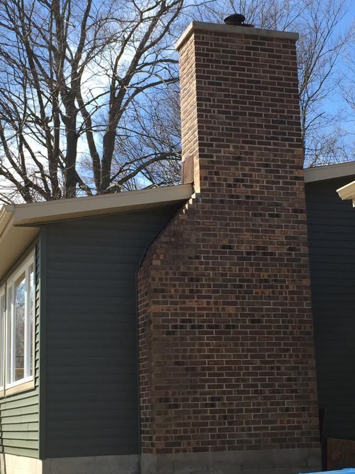 A large brick chimney is on the side of a house.