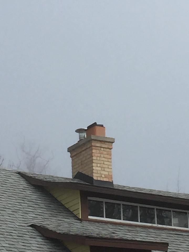A chimney on the roof of a house against a cloudy sky