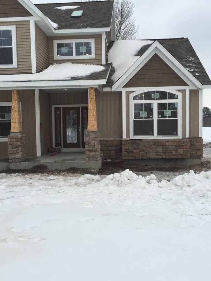 A house with snow on the roof is sitting in the snow.